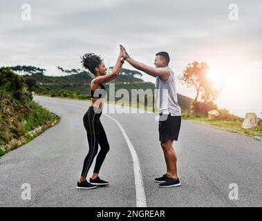 Diese kleine Unterstützung hilft wirklich. Ein sportliches, junges Paar, das sich beim Sport im Freien gegenseitig High Five holt. Stockfoto