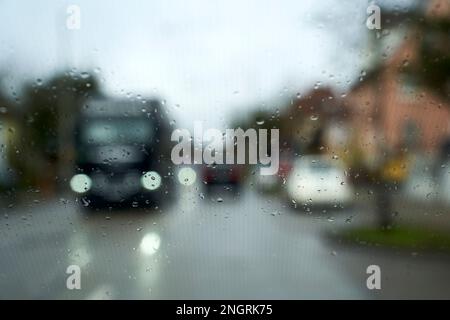 Straße bei starkem Regen. Auf der Straße oder auf der Straße fällt Wasser oder es regnet vor dem Fahrzeug. Auto im Regen fahren. Unscharfer Hintergrund. Stockfoto