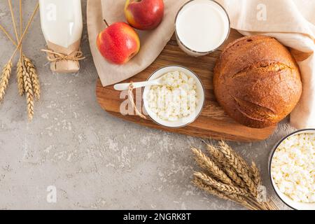 Traditionelle Leckereien und Symbole des jüdischen Frühlingsfeiertags von Shavuot auf grauem Zementhintergrund mit einer Kopie des Raums Stockfoto