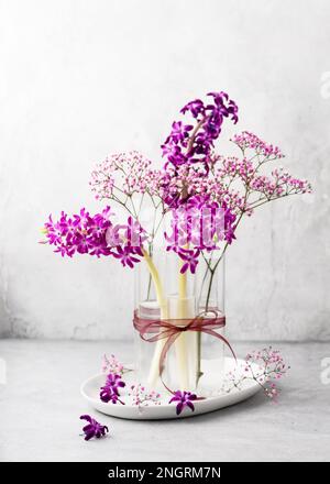 Wunderschöner Strauß aus lila Hyazinthen und rosa Zigeuner-Blumen in einer Glasvase. Frühlingsblütenanordnung. Pastellfarben im Vintage-Stil. Stockfoto
