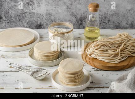 Verschiedene Arten von Teig. Teig für Teigtaschen, Teigtaschen, Pasties, Nudeln und Lasagne-Blätter auf weißem Holzhintergrund Stockfoto