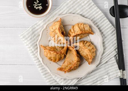 Gyoza mit Füllung und Sojasoße. Verschiedene Gyoza sind auf einem Teller, neben Sojasoße und Sushi-Stäbchen Stockfoto