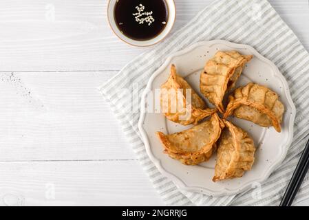 Gyoza mit Füllung und Sojasoße. Verschiedene Gyoza sind auf einem Teller, neben Sojasoße und Sushi-Stäbchen Stockfoto