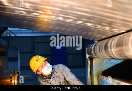 HOLINGOL, CHINA - 19. FEBRUAR 2023 - Ein Mitarbeiter inspiziert die Produktionslinie für hochwertige Aluminiumfolien in der Werkstatt der inneren Mongolei Liansheng New Stockfoto