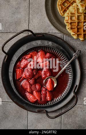 Frische Erdbeersoße auf einem Teller. Auf grauem Hintergrund in Form einer Waffel Stockfoto