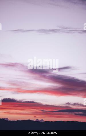 Ein faszinierender Blick auf den Himmel, mit sanften, rosa, violetten und lila geschwollenen Wolken, die sich nach oben erstrecken, als ob sie nach dem Himmel greifen würden. Stockfoto