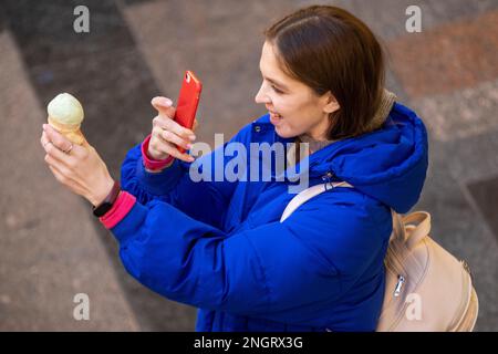 Moskau, Russland. 17. Februar 2023. Eine schöne Frau fotografiert das Eis, das sie im KAUGUMMI-Kaufhaus im Zentrum von Moskau, Russland, gekauft hat Stockfoto