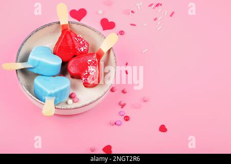 Verschiedene Arten von Eis aus dem Eisbein auf rosa Hintergrund. Stimmungsvolles Sommerkonzept. Draufsicht, flach liegend, Kopierbereich Stockfoto