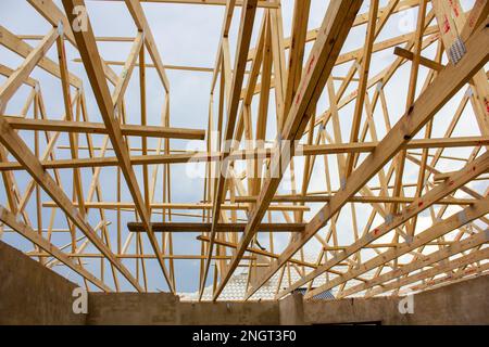 Holzrahmen eines Gitters aus Dachbalken auf einem Gebäude im Bau, auf dem keine Dachziegel platziert sind. Stockfoto