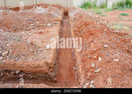 Schwindende Perspektive auf Fundamentgräben, die für den Bau eines neuen Gebäudes gegraben werden. Stockfoto