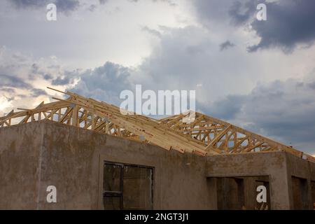 Unlackierte Putzwände und Holzdachbalken eines im Bau befindlichen Hauses. Stockfoto