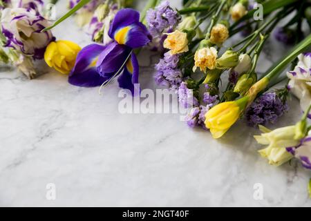 Rahmen aus verschiedenen Blumen auf Marmorhintergrund. Flach liegend, Draufsicht, Kopierbereich. Osterkomposition. Romantisches saisonales Designelement. Herzlichen Glückwunsch Stockfoto