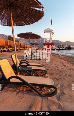 Leerer Strand mit Sonnenliegen und Sonnenschirmen am frühen Morgen an einem sonnigen Tag in Belek, Antalya, Türkei. Stockfoto