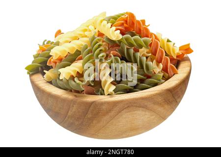 Rohe dreifarbige Fusilli- oder Rotini-Pasta (traditioneller Geschmack, Tomaten- und Spinatgeschmack) in einer Holzschüssel, isoliert auf weißem Hintergrund. Datei enthält Beschneidungspfad Stockfoto