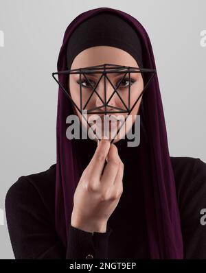 Muslimische Frau in moderner, stylischer Kleidung und isoliertem Hidschab auf grauem Hintergrund. Verschiedene Menschen modellieren Hidschab-Modekonzept. Gesichtserkennung und Stockfoto