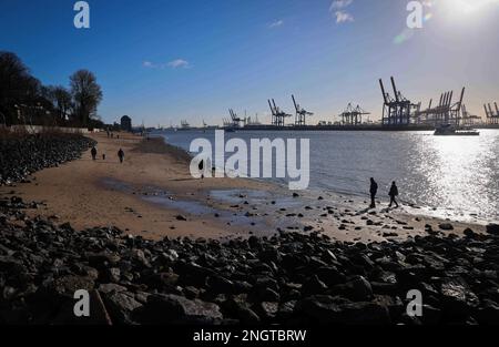 Hamburg, Deutschland. 19. Februar 2023. Passanten gehen am Elbstrand in der Nähe von Oevelgönne in hellem Sonnenschein entlang. Kredit: Christian Charisius/dpa/Alamy Live News Stockfoto