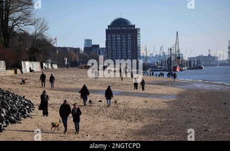 Hamburg, Deutschland. 19. Februar 2023. Passanten gehen am Elbstrand in der Nähe von Oevelgönne in hellem Sonnenschein entlang. Kredit: Christian Charisius/dpa/Alamy Live News Stockfoto