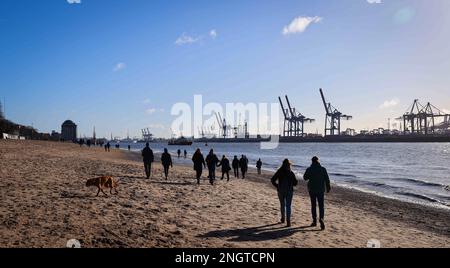 Hamburg, Deutschland. 19. Februar 2023. Passanten gehen am Elbstrand in der Nähe von Oevelgönne in hellem Sonnenschein entlang. Kredit: Christian Charisius/dpa/Alamy Live News Stockfoto