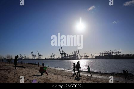 Hamburg, Deutschland. 19. Februar 2023. Passanten gehen am Elbstrand in der Nähe von Oevelgönne in hellem Sonnenschein entlang. Kredit: Christian Charisius/dpa/Alamy Live News Stockfoto