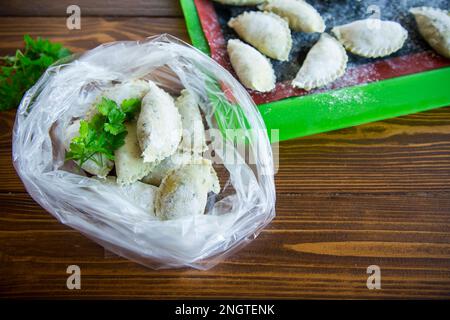 Rohe, grüne Teigknödel mit Petersilie, Dill. Rohe Knödel in einer Tüte auf einem Holztisch. Stockfoto