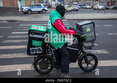 Moskau, Russland. 17. Februar 2023. Ein Kurier des Vkusvill Food Delivery Service liefert eine Bestellung an einen Kunden in der Tverskaya Street im Zentrum von Moskau, Russland Stockfoto