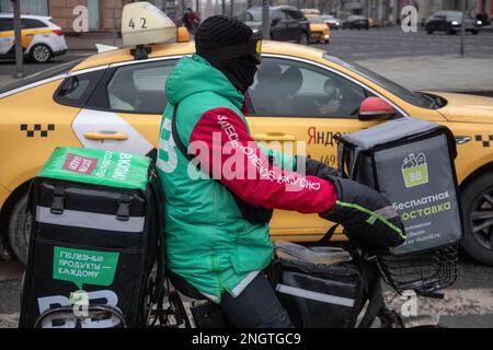 Moskau, Russland. 17. Februar 2023. Ein Kurier des Vkusvill Food Delivery Service liefert eine Bestellung an einen Kunden in der Tverskaya Street im Zentrum von Moskau, Russland Stockfoto