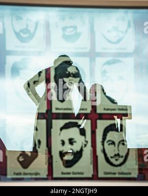 Hanau, Deutschland. 19. Februar 2023. Das Denkmal der Gebrüder Grimm auf dem Marktplatz spiegelt sich in einem Fenster des Rathauses von Hanau wider, wo Bilder die neun Opfer des rassistischen Angriffs vor drei Jahren auf einem Poster zeigen. Ein 43-jähriger Deutscher hatte neun Menschen aus rassistischen Motiven erschossen und dann seine Mutter und sich selbst getötet. Kredit: Frank Rumpenhorst/dpa/Alamy Live News Stockfoto