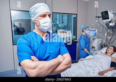 Das medizinische Team der Intensivstation betreut die im Krankenhausbett liegende Patientin. INTENSIVSTATION Stockfoto