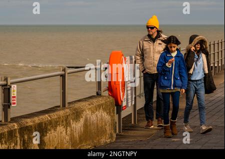 Margate, Großbritannien. 18. Februar 2023 Besucher besuchen Antony Gormley: Ein anderes Mal, am Nayland Rock, neben dem Turner Contemporary, in Margate. Es ist eine von hundert soliden gusseisernen Figuren von Antony Gormley, die die Erfahrung des menschlichen Wesens erforschen. Leben an der Margate Küste. Kredit: Guy Bell/Alamy Live News Stockfoto