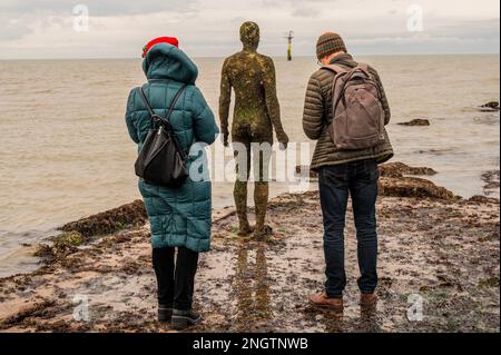 Margate, Großbritannien. 18. Februar 2023 Besucher besuchen Antony Gormley: Ein anderes Mal, am Nayland Rock, neben dem Turner Contemporary, in Margate. Das Werk wird erst enthüllt, wenn die Flut zurückgeht. Es ist eine von hundert soliden gusseisernen Figuren von Antony Gormley, die die Erfahrung des menschlichen Wesens erforschen. Leben an der Margate Küste. Kredit: Guy Bell/Alamy Live News Stockfoto