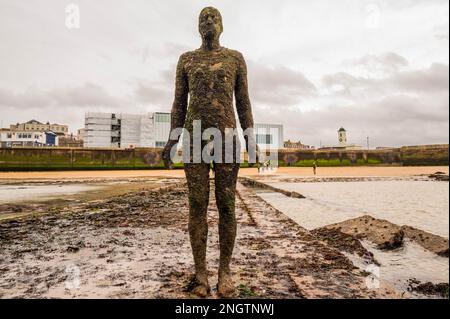 Margate, Großbritannien. 18. Februar 2023 Besucher besuchen Antony Gormley: Ein anderes Mal, am Nayland Rock, neben dem Turner Contemporary, in Margate. Das Werk wird erst enthüllt, wenn die Flut zurückgeht. Es ist eine von hundert soliden gusseisernen Figuren von Antony Gormley, die die Erfahrung des menschlichen Wesens erforschen. Leben an der Margate Küste. Kredit: Guy Bell/Alamy Live News Stockfoto