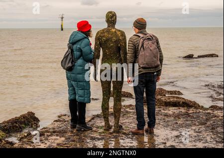 Margate, Großbritannien. 18. Februar 2023 Besucher besuchen Antony Gormley: Ein anderes Mal, am Nayland Rock, neben dem Turner Contemporary, in Margate. Das Werk wird erst enthüllt, wenn die Flut zurückgeht. Es ist eine von hundert soliden gusseisernen Figuren von Antony Gormley, die die Erfahrung des menschlichen Wesens erforschen. Leben an der Margate Küste. Kredit: Guy Bell/Alamy Live News Stockfoto