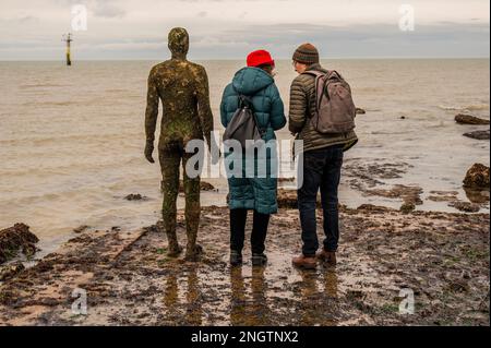 Margate, Großbritannien. 18. Februar 2023 Besucher besuchen Antony Gormley: Ein anderes Mal, am Nayland Rock, neben dem Turner Contemporary, in Margate. Das Werk wird erst enthüllt, wenn die Flut zurückgeht. Es ist eine von hundert soliden gusseisernen Figuren von Antony Gormley, die die Erfahrung des menschlichen Wesens erforschen. Leben an der Margate Küste. Kredit: Guy Bell/Alamy Live News Stockfoto