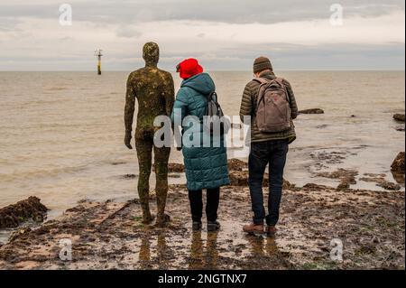 Margate, Großbritannien. 18. Februar 2023 Besucher besuchen Antony Gormley: Ein anderes Mal, am Nayland Rock, neben dem Turner Contemporary, in Margate. Das Werk wird erst enthüllt, wenn die Flut zurückgeht. Es ist eine von hundert soliden gusseisernen Figuren von Antony Gormley, die die Erfahrung des menschlichen Wesens erforschen. Leben an der Margate Küste. Kredit: Guy Bell/Alamy Live News Stockfoto