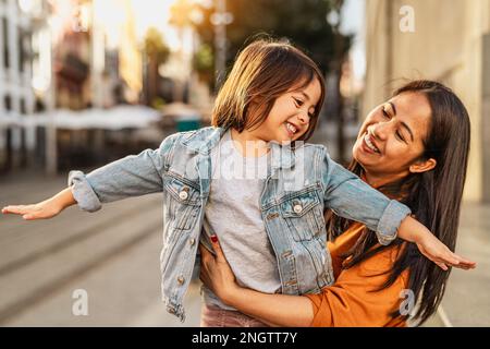 Glückliche Filipina Mutter mit ihrer Tochter, die Spaß im Stadtzentrum hat - nette Familie draußen Stockfoto