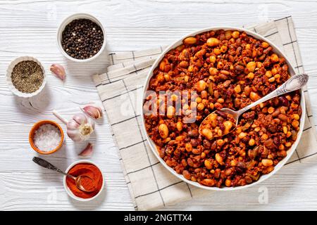 Bohnen und Würstchen mit Kidney Beans, großen Nordbohnen, Schwarzäugigen Erbsen, Pinto Beans, Kichererbsen, Fleisch- und Tomatensoße in Backform auf weißem w Stockfoto