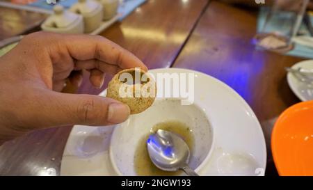 Ein indischer Mann hält Panipuri oder Golgappa oder Puchkas mit Kartoffelmasala drin. Ein beliebtes indisches Chat-Menü. Stockfoto