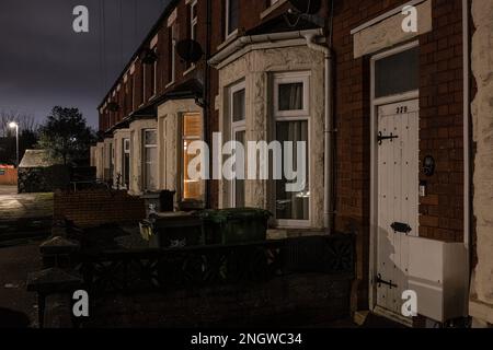 Straße mit Terrassenhäusern der Mittelschicht/Arbeiterklasse, deren Autos nachts auf der Straße in einem Vorort von Cardiff geparkt sind Stockfoto