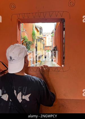 Ein Tourist blickt auf den Canal di Reno von einem offenen Fenster in Bologna, Italien Stockfoto