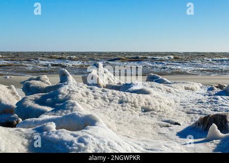 Nahaufnahme des eisigen Meeres, gefrorene Wellen, Felsen und Sonnenblendung auf dem Eis Stockfoto