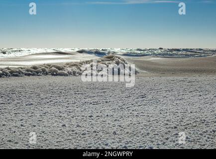 Nahaufnahme des eisigen Meeres, gefrorene Wellen, Felsen und Sonnenblendung auf dem Eis Stockfoto