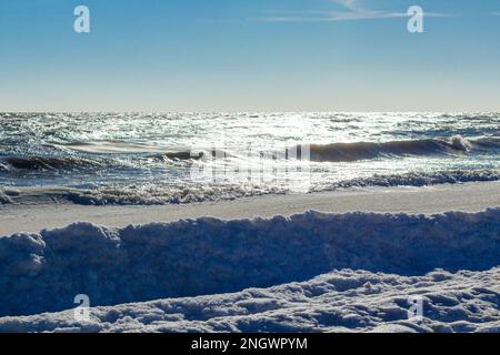 Nahaufnahme des eisigen Meeres, gefrorene Wellen, Felsen und Sonnenblendung auf dem Eis Stockfoto