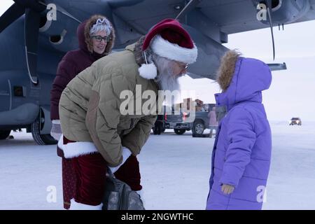 Santa und Mrs. Claus begrüßen ein Kind am Nuiqsut Flughafen im Rahmen der Operation Santa Claus am 29. November 2022. Die Clauses und mehr als drei Dutzend Elfen von der Alaska Air and Army National Guard haben sich mit der Heilsarmee zusammengetan, um 191 Kindern Geschenke, Hygieneartikel und Bücher im Wert von 1.420 Pfund zu liefern. Alaska Air National Guard HC-130J Combat King II. Feierte 67 Jahre Operation Santa Claus, einen 176.-Flügel, und diente als Santa's Schlitten, um der Gemeinde North Slope Borough eine gute Nachricht zu bringen (Alaska Air National Guard Foto von Major Chelsea Aspelund) Stockfoto