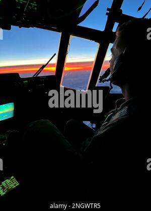 Matt Soukup, Major der Luftwaffe Alaska, ein Pilot der 211.. Rettungsschwadron, genießt einen lebendigen Sonnenuntergang in Alaska, während er den Weihnachtsmann, Mrs. Claus und drei Dutzend Helferelfer nach Abschluss der Operation Santa Claus in Nuiqsut über den 176.. Flügel HC-130J Combat King II zur Joint Base Elmendorf-Richardson fliegt. Die Operation Santa Claus ist das alljährliche Programm der Alaska National Guard für die Zusammenarbeit und Unterstützung der Gemeinschaft, das Kindern in entlegenen Gemeinden im ganzen Bundesstaat Geschenke überreicht. In Partnerschaft mit der Heilsarmee lieferten der Weihnachtsmann, Mrs. Claus und mehr als drei Dutzend Elfen 1.420 Pfund Geschenke. Stockfoto