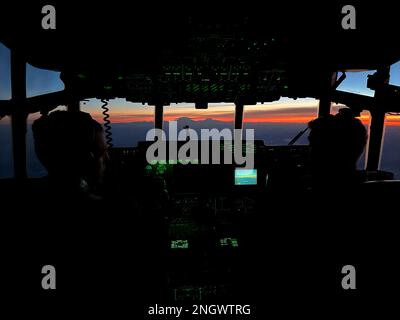 Alaska Air National Guard Majors Dan Kozak, links, Und Matt Soukup, beide Piloten des 211.. Rettungsgeschwaders, genießen einen lebendigen Sonnenuntergang in Alaska, während sie den Weihnachtsmann, Mrs. Claus und drei Dutzend Elfen nach Abschluss der Operation Santa Claus in Nuiqsut über den 176.. Flügel HC-130J Combat King II zur Joint Base Elmendorf-Richardson fliegen. Die Operation Santa Claus ist das alljährliche Programm der Alaska National Guard für die Zusammenarbeit und Unterstützung der Gemeinschaft, das Kindern in entlegenen Gemeinden im ganzen Bundesstaat Geschenke überreicht. In Zusammenarbeit mit der Heilsarmee, dem Weihnachtsmann, Mrs. Claus und mehr als drei Dutzend Elfen Stockfoto