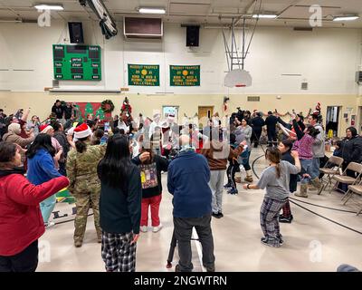 Santa und Mrs. Claus nehmen am 29. November 2022 an der Trapper School in Nuiqsut, Alaska, an einem traditionellen Inupiat-Eskimo-Tanz Teil. Die Operation Santa Claus ist das alljährliche Programm der Alaska National Guard für die Zusammenarbeit und Unterstützung der Gemeinschaft, das Kindern in entlegenen Gemeinden im ganzen Bundesstaat Geschenke überreicht. In Zusammenarbeit mit der Heilsarmee lieferten der Weihnachtsmann, Frau Claus und mehr als drei Dutzend Elfen 1.420 Pfund Geschenke, Rucksäcke, Hygieneartikel und Bücher an 191 Kinder in Nuiqsut. (Alaska National Guard Foto von 1. LT. Balinda O’Neal) Stockfoto
