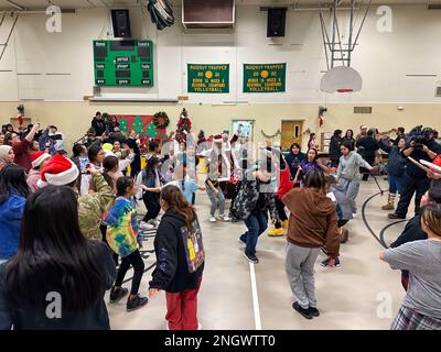 Santa und Mrs. Claus nehmen am 29. November 2022 an der Trapper School in Nuiqsut, Alaska, an einem traditionellen Inupiat-Eskimo-Tanz Teil. Die Operation Santa Claus ist das alljährliche Programm der Alaska National Guard für die Zusammenarbeit und Unterstützung der Gemeinschaft, das Kindern in entlegenen Gemeinden im ganzen Bundesstaat Geschenke überreicht. In Zusammenarbeit mit der Heilsarmee lieferten der Weihnachtsmann, Frau Claus und mehr als drei Dutzend Elfen 1.420 Pfund Geschenke, Rucksäcke, Hygieneartikel und Bücher an 191 Kinder in Nuiqsut. (Alaska National Guard Foto von 1. LT. Balinda O’Neal) Stockfoto