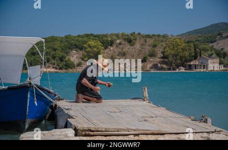 Handleinenfischerei oder Handleinenfischerei. Albanischer Fischer auf einem Butrint-See in KSAMIL, ALBANIEN Stockfoto