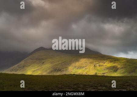 Doolough Valley, Glenummera und Glencullin Bergketten, beleuchtet von Sonnenlicht und teilweise bedeckt von dunklen Wolken, County Mayo, Irland Stockfoto