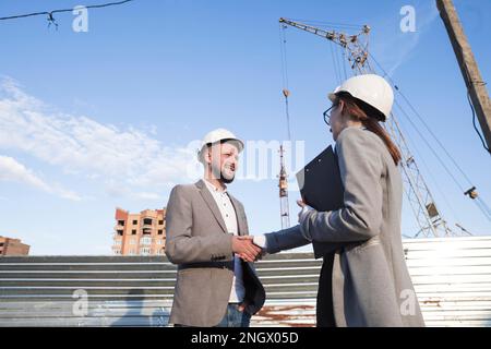 Lächelnde Ingenieure, die sich die Hände schütteln Baustellenarchitektur Projekt. Hochauflösendes Foto Stockfoto